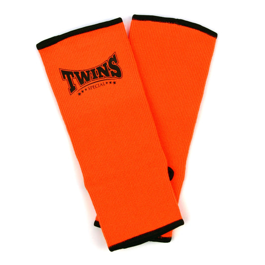Orange ankle guards with black trim and Twins Special logo on a white background
