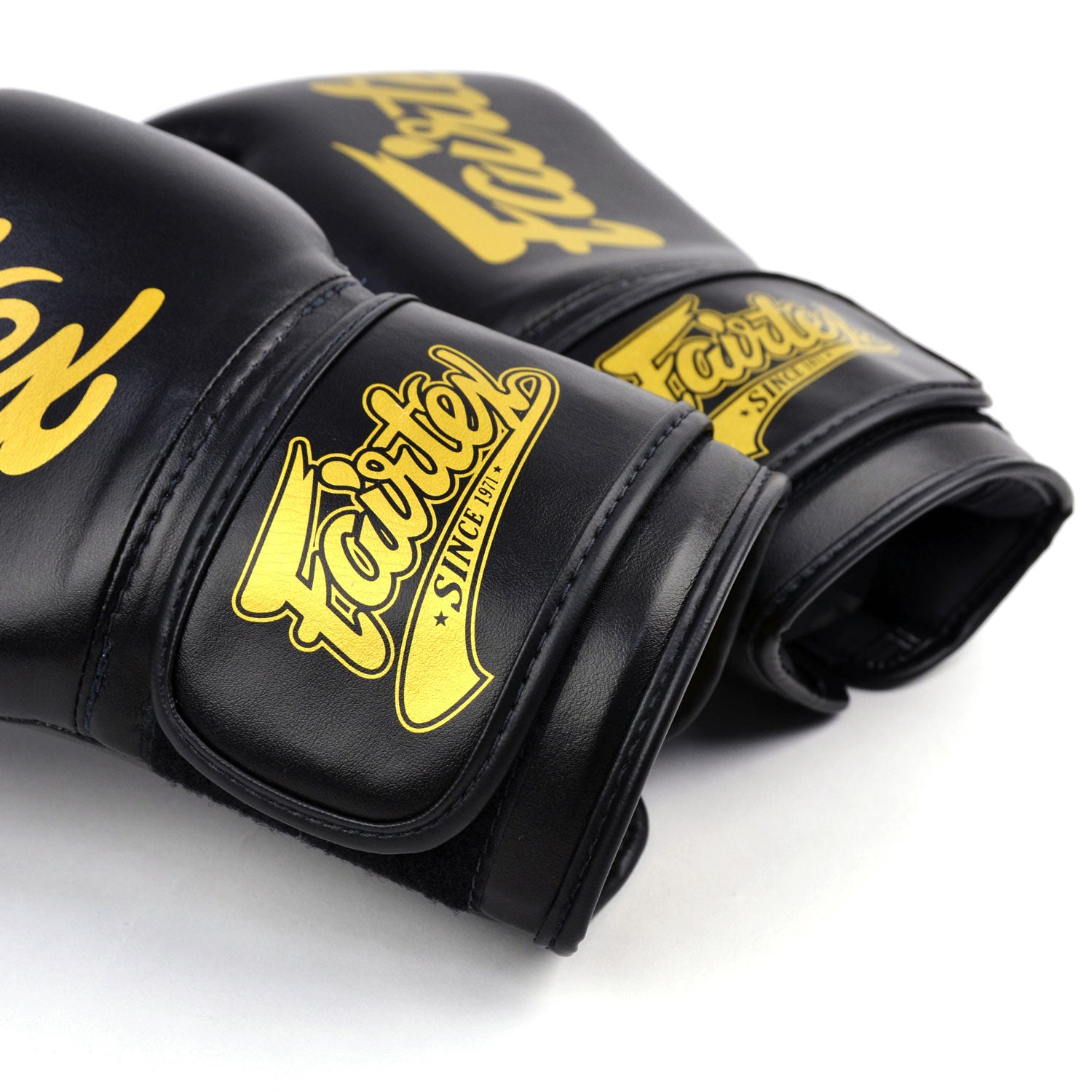 Black boxing gloves with gold 'Fairtex' branding on a white background