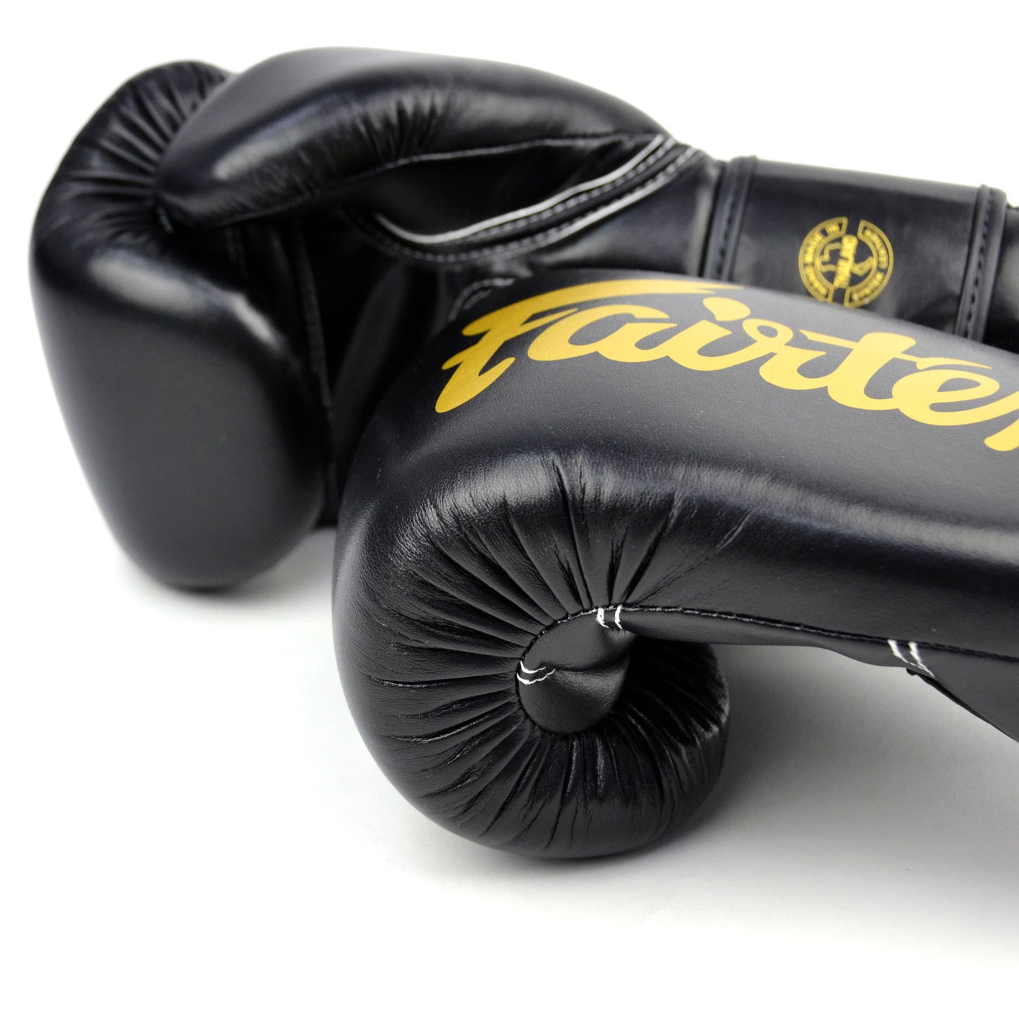 Black boxing gloves with gold 'Fairtex' branding on a white background