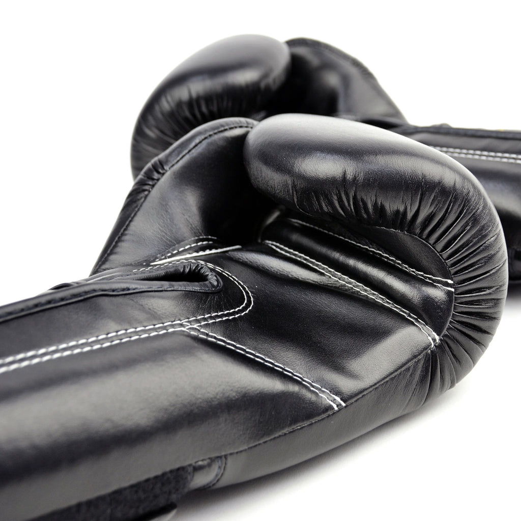 Black boxing gloves with gold 'Fairtex' branding on a white background