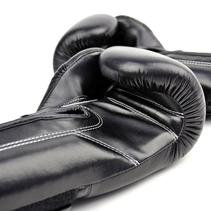 Black boxing gloves with gold 'Fairtex' branding on a white background