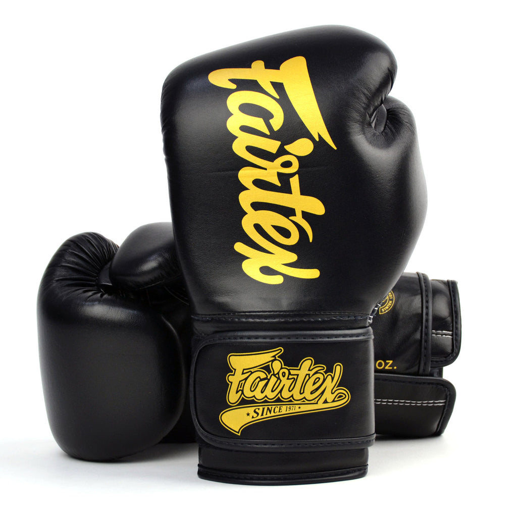Black boxing gloves with gold 'Fairtex' branding on a white background