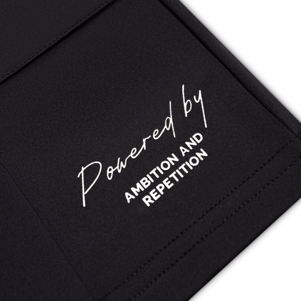 Black bag with white text 'Powered by Ambition and Repetition' on a white background