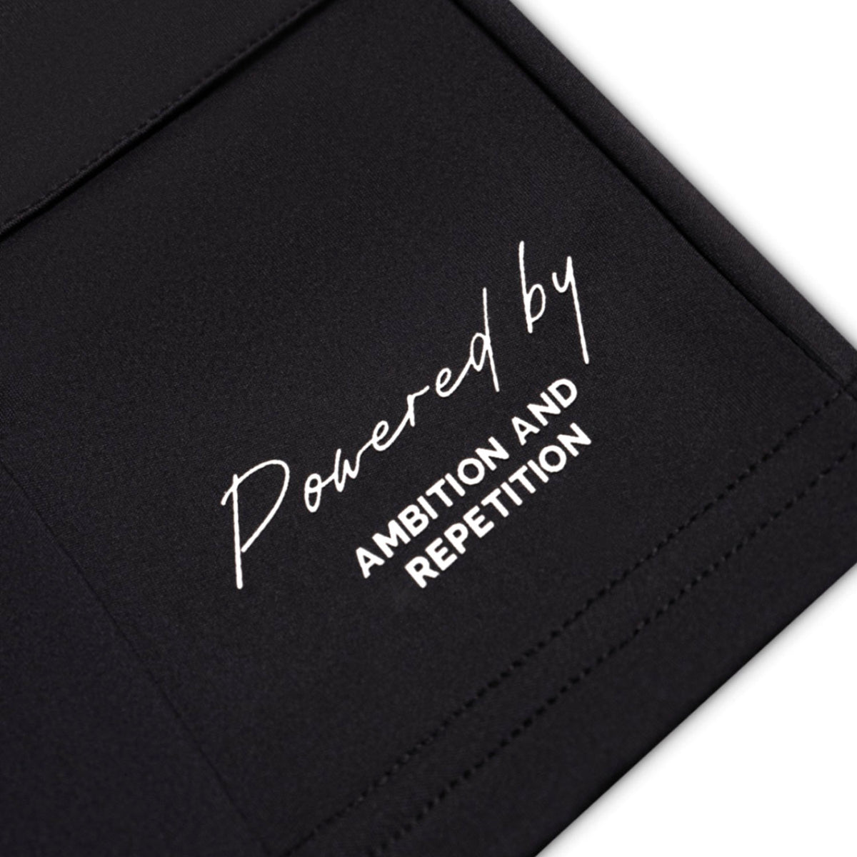 Black bag with white text 'Powered by Ambition and Repetition' on a white background