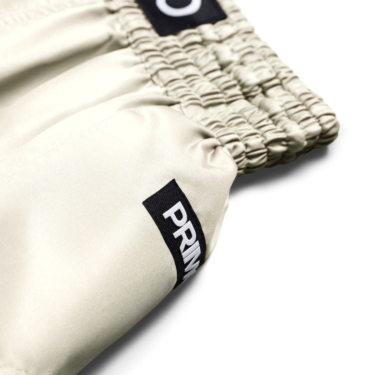 Close-up of beige shorts with a brand label on a white background