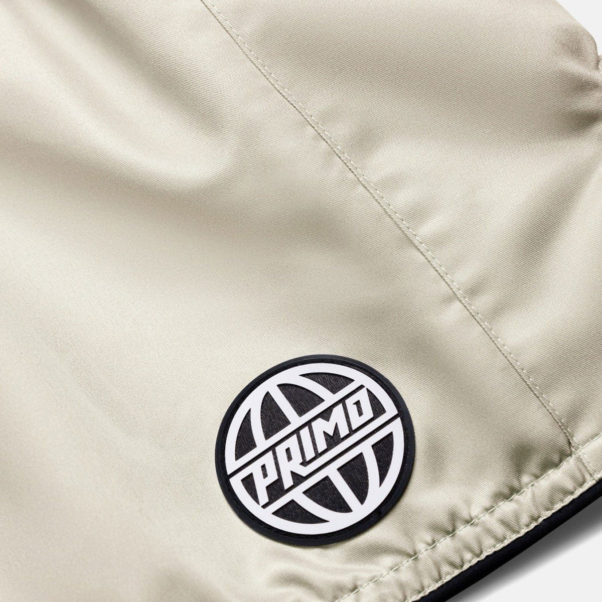 Close-up of a beige fabric surface with a black and white 'Primo' logo patch.