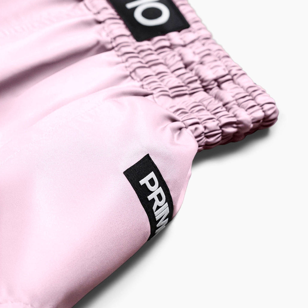 Close-up of pink shorts with a brand logo on a white background