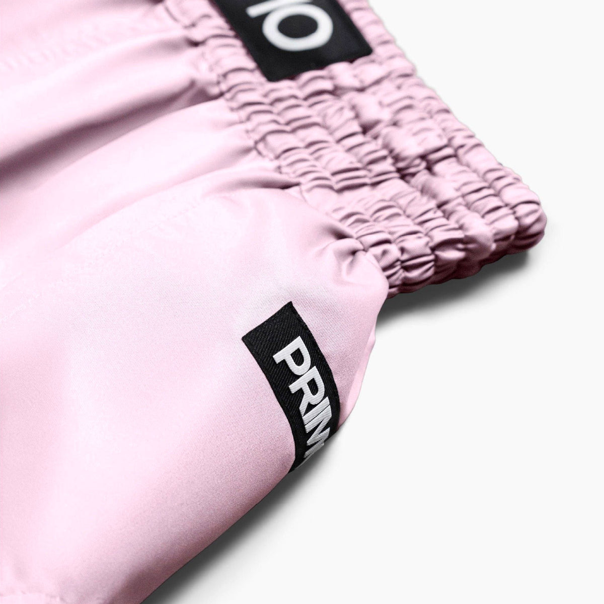 Close-up of pink shorts with a brand logo on a white background
