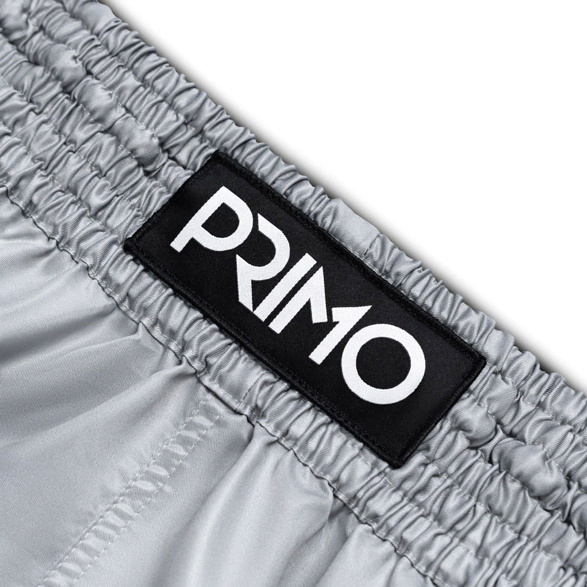 Close-up of gray shorts with a black 'Primo' logo label.