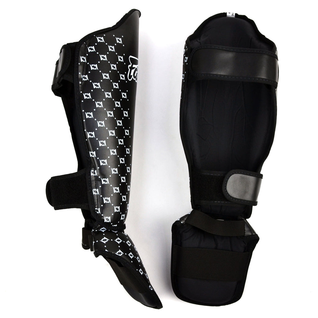 Black shin guards with white pattern and 'Fairtex' branding on a white background