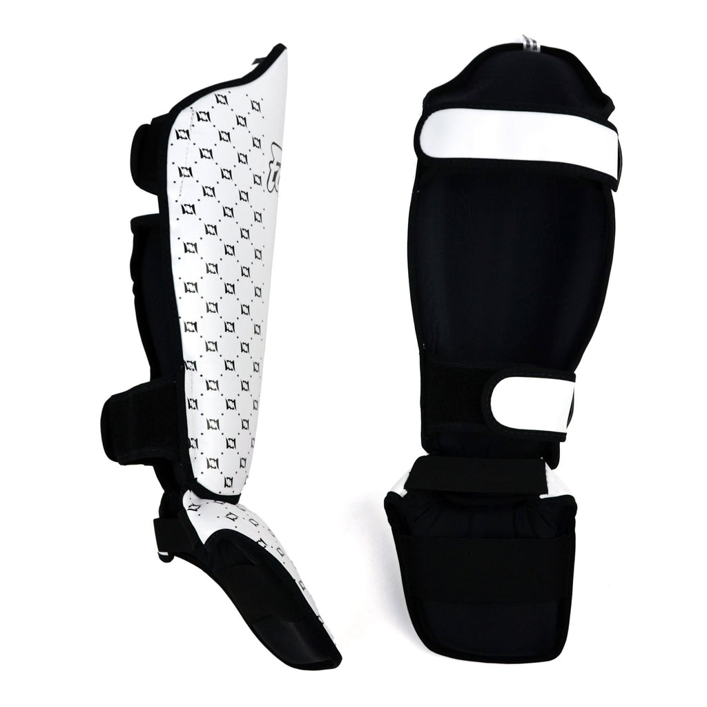 Pair of white shin guards with black patterns and 'Fairtex' branding on a white background