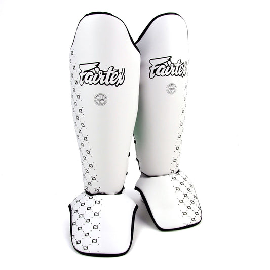 Pair of white shin guards with black patterns and 'Fairtex' branding on a white background