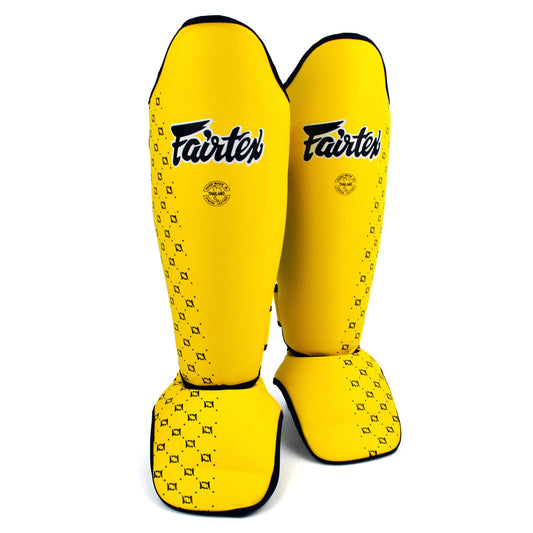Yellow shin guards with Fairtex logo on a white background