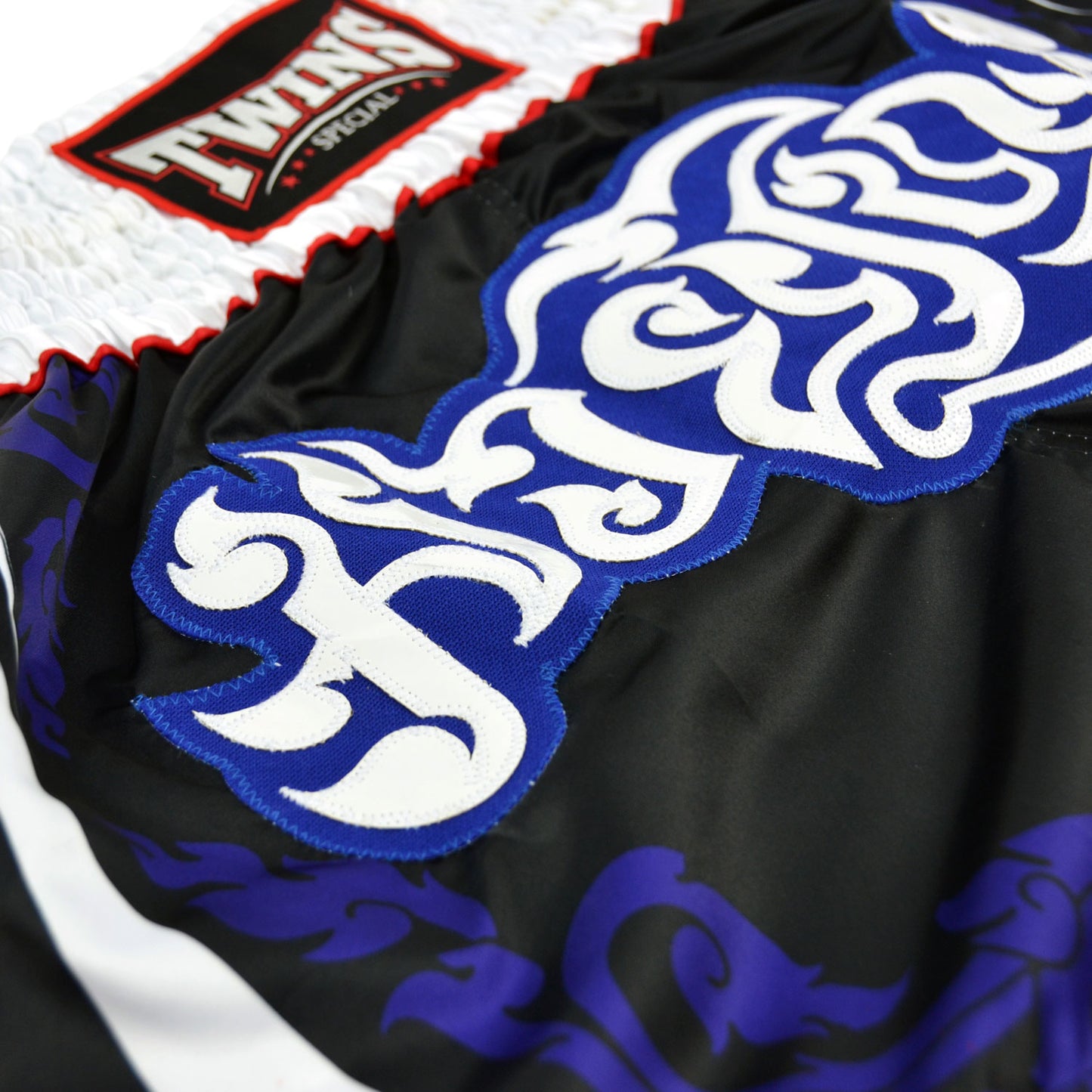 Black boxing shorts with red and blue designs and Twins Special logo on a white background