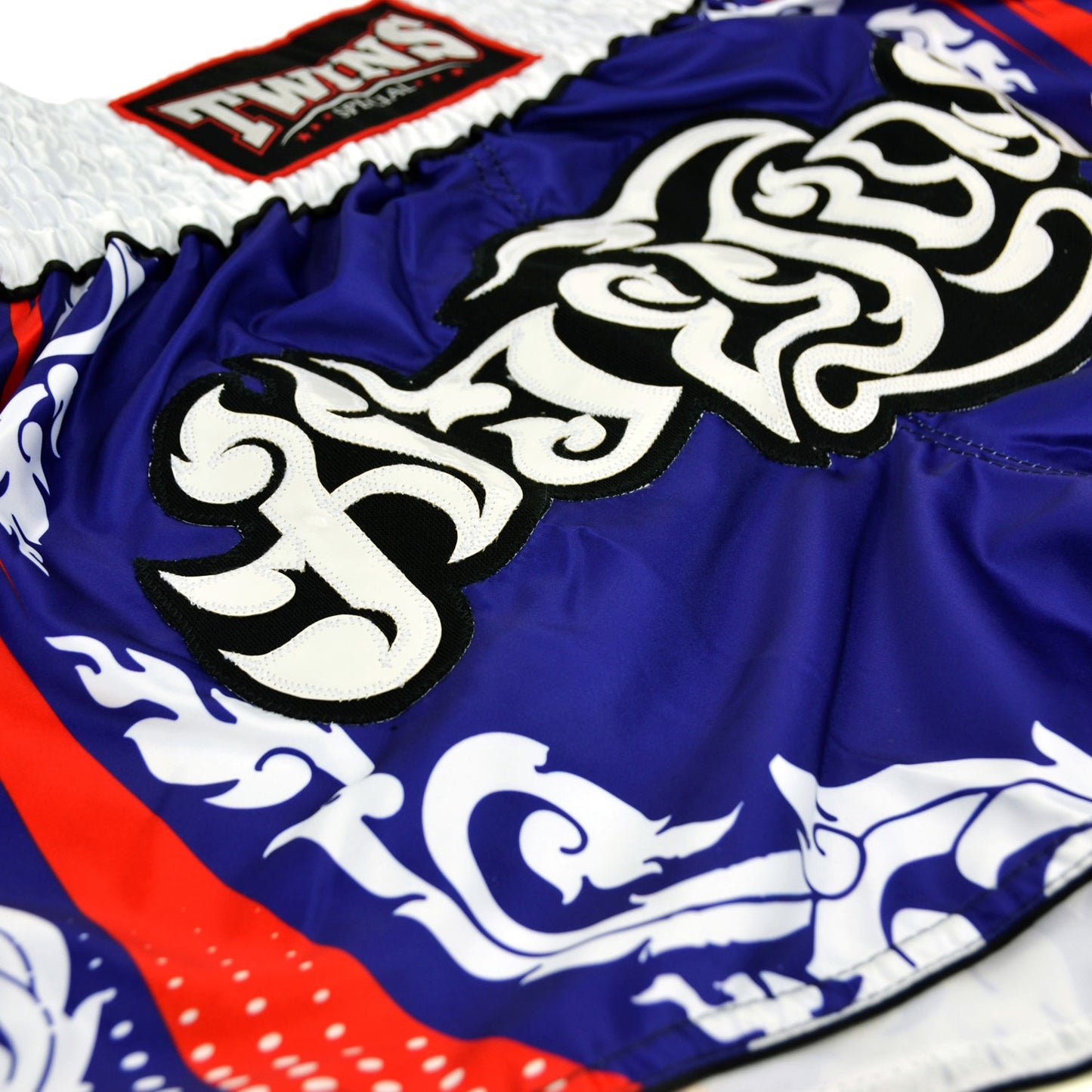 Blue and white Muay Thai shorts with red accents and Twins Special logo on a white background
