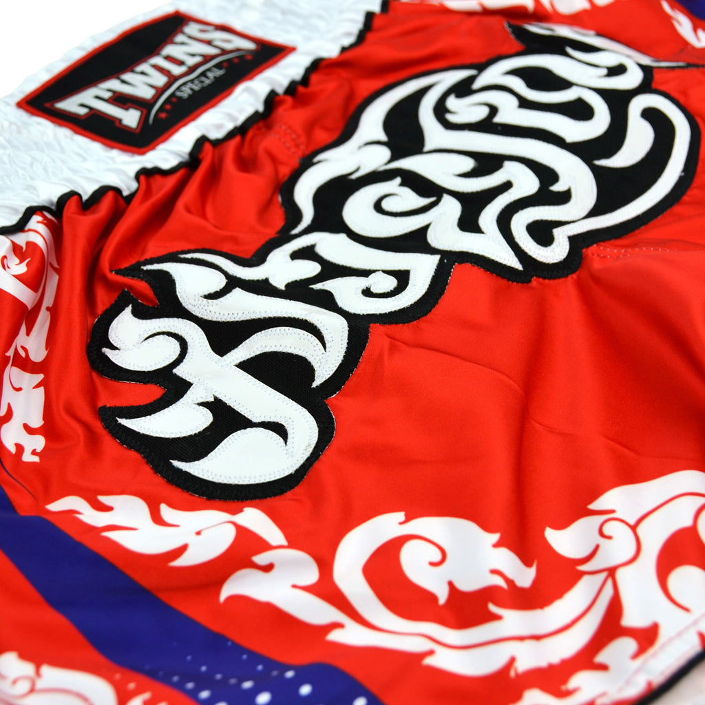 Red boxing shorts with white and blue patterns and 'Twins' branding on a white background