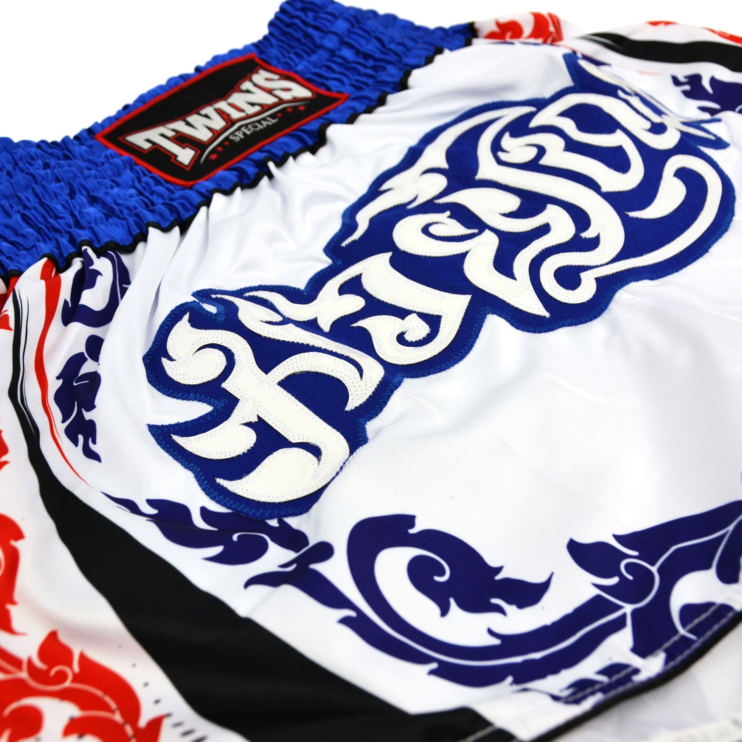 White boxing shorts with blue and red patterns and Twins Special logo on a white background